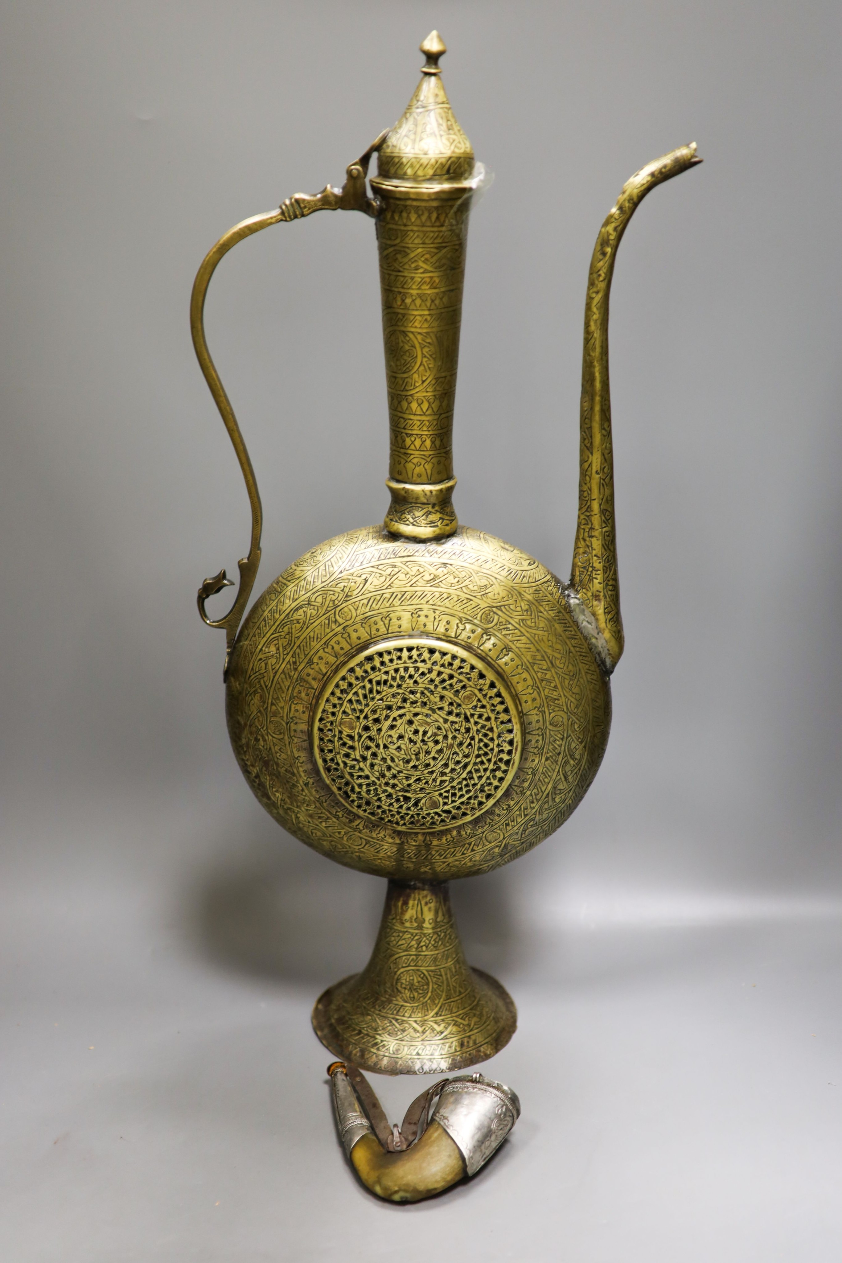 A Persian engraved brass ewer and Middle-eastern horn and white metal priming shot flask 57cm